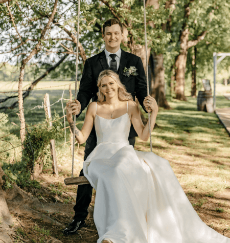 Bride seated on a wooden swing with the groom standing behind her at an outdoor Tampa wedding