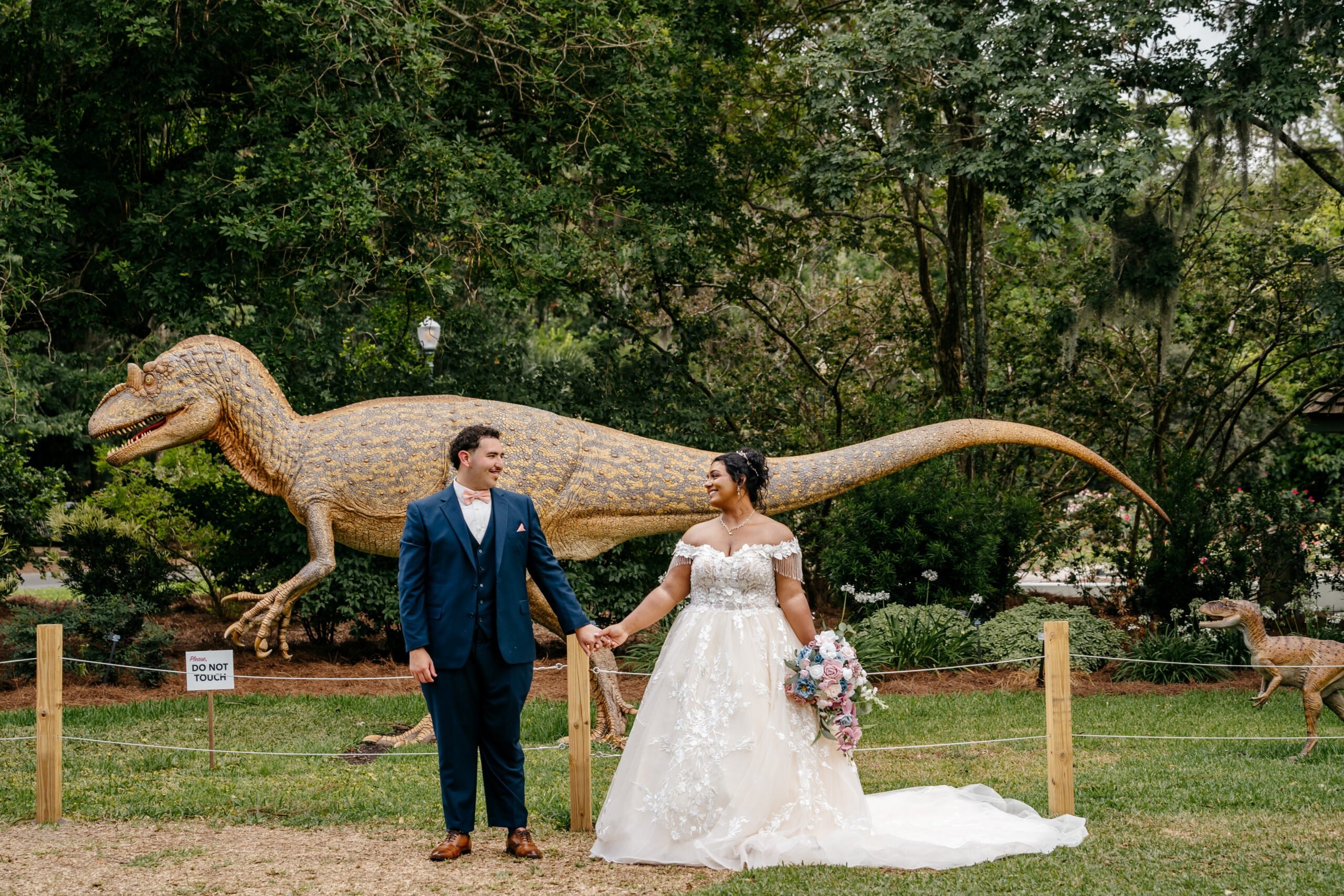 Newlyweds posing together in front of a dinosaur display during a playful Florida wedding portrait.