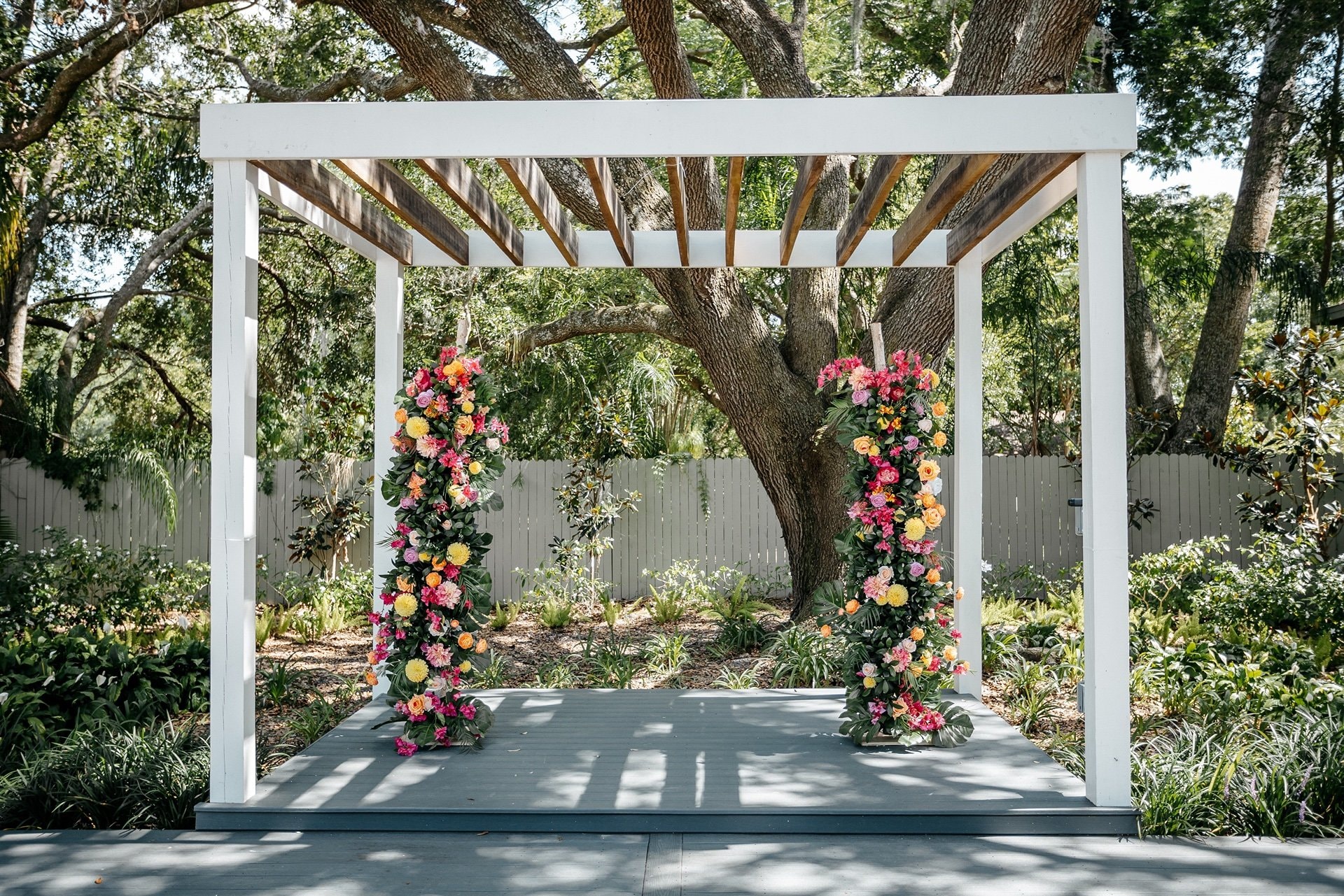 A pergola is decorated with greenery and colorful flowers in a garden in Central Florida