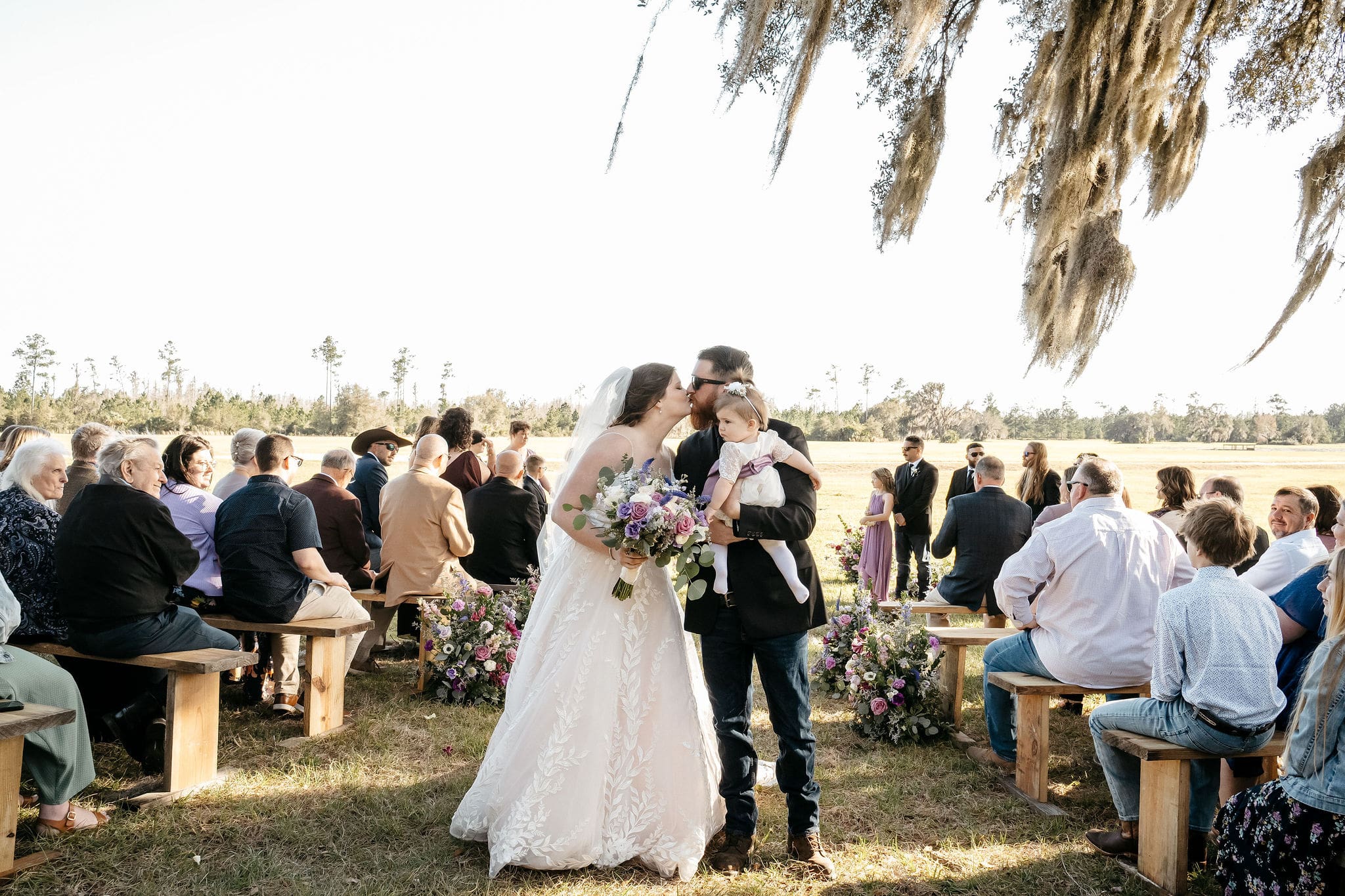 Groom carrying his baby while kissing his bride | Cherished Memories Studio
