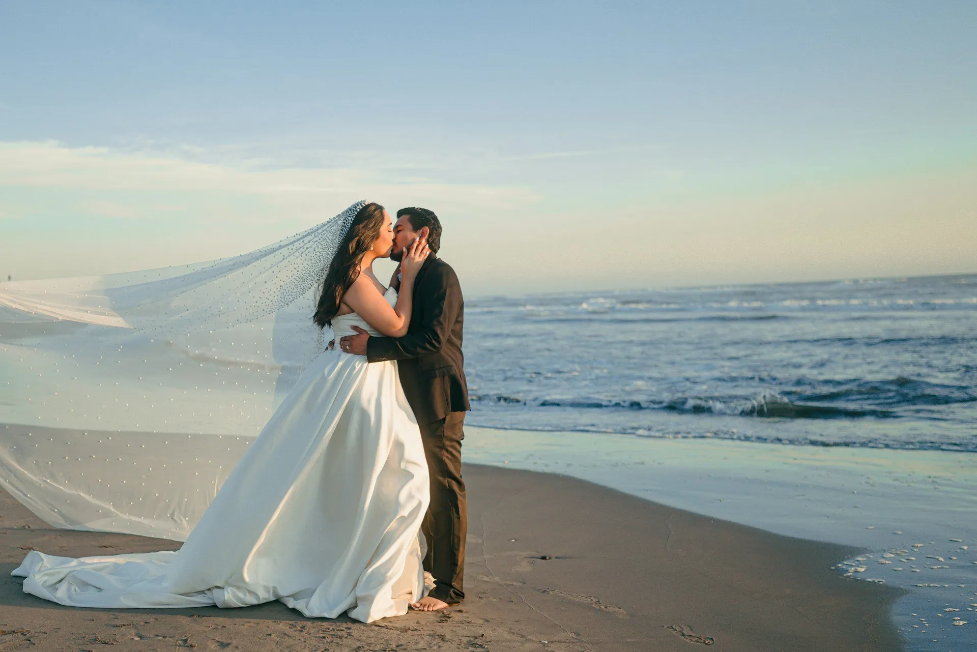 Bride and groom embracing on a Florida beach with ocean waves in the background.