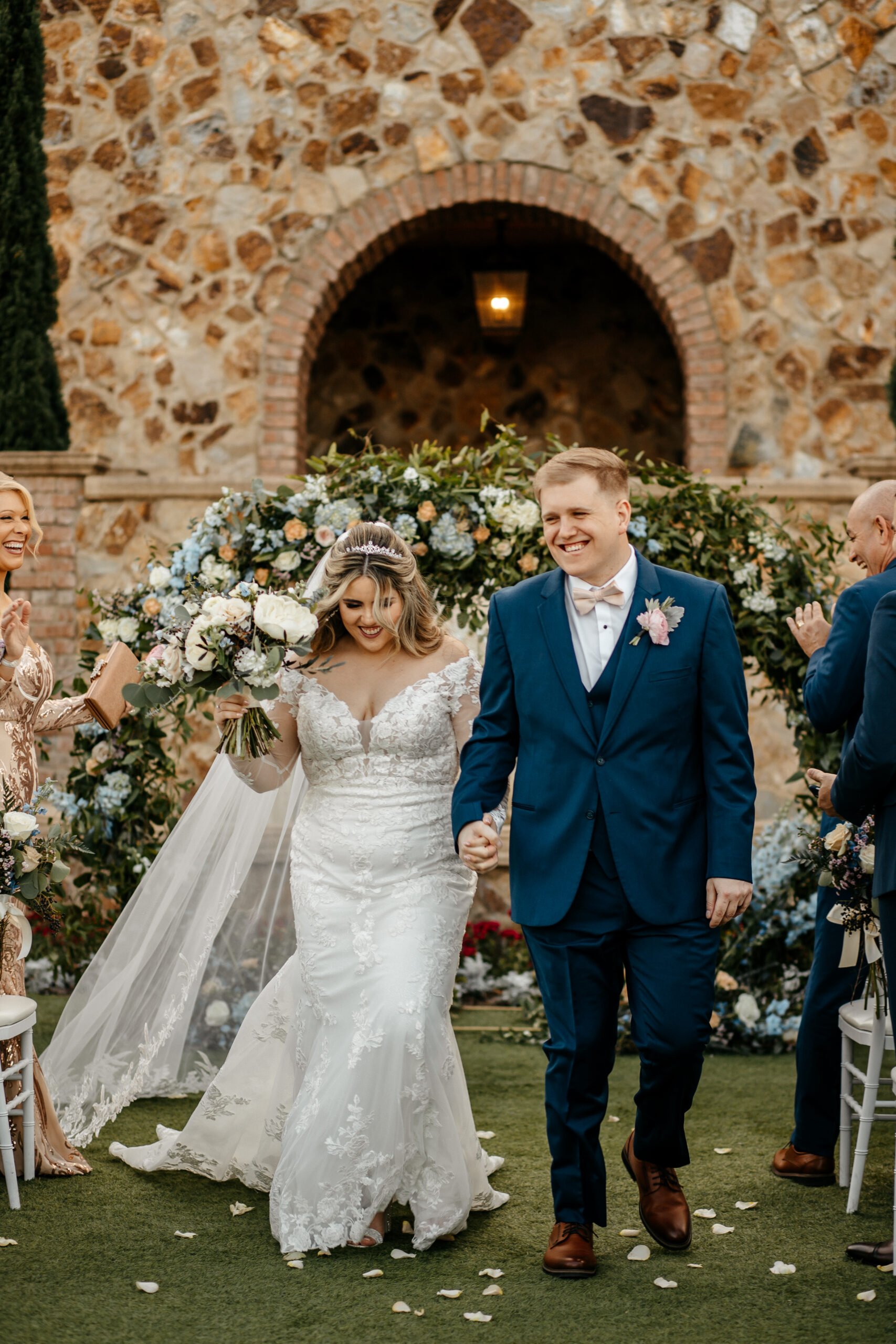 Bride and groom hold hands and smile at their friends and family as they walk down the aisle after saying "I do" at their Bella Collina Orlando wedding