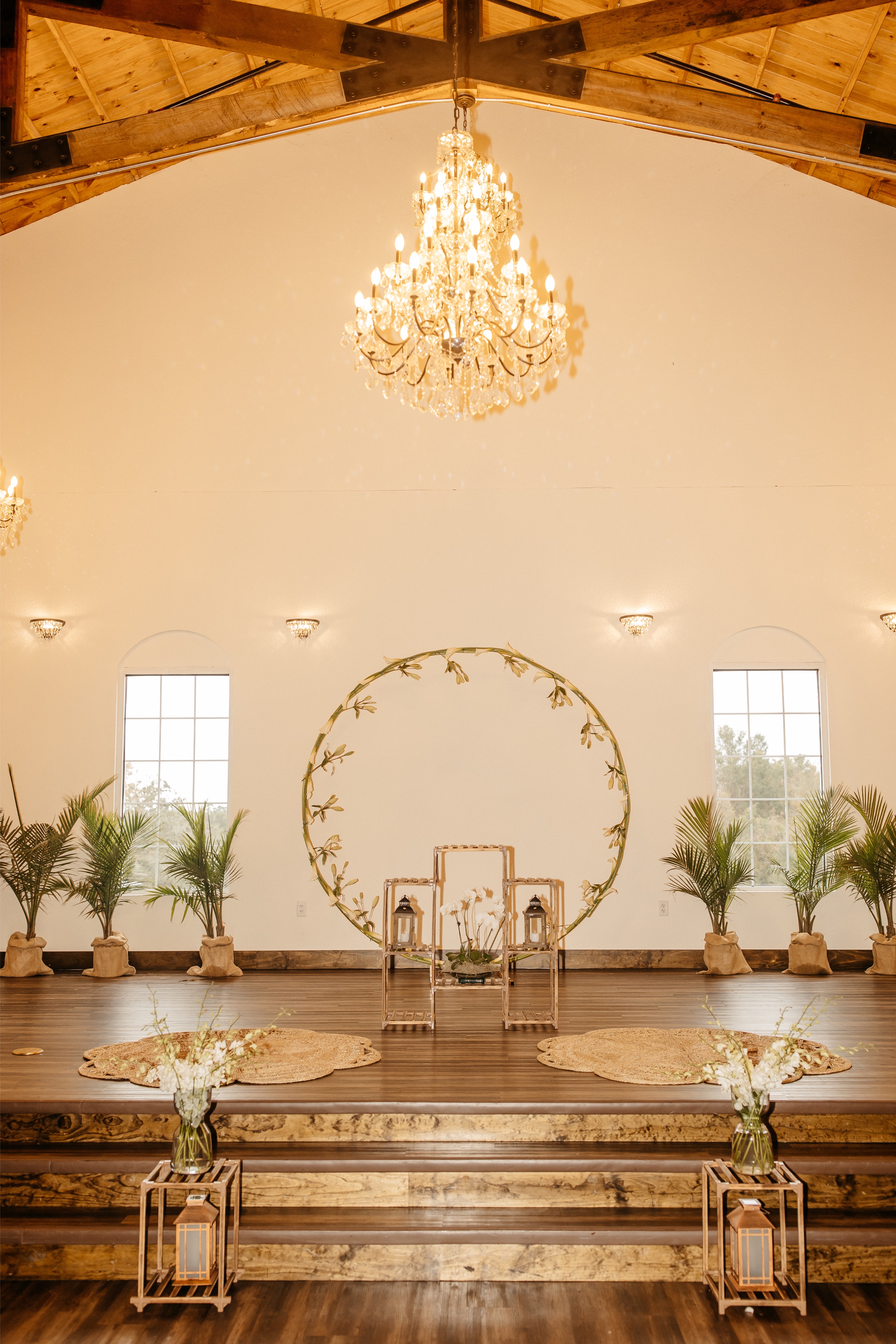 A beautiful wedding backdrop with greenery and a circular display with a bright, crystal chandelier at a wedding venue in Central Florida 