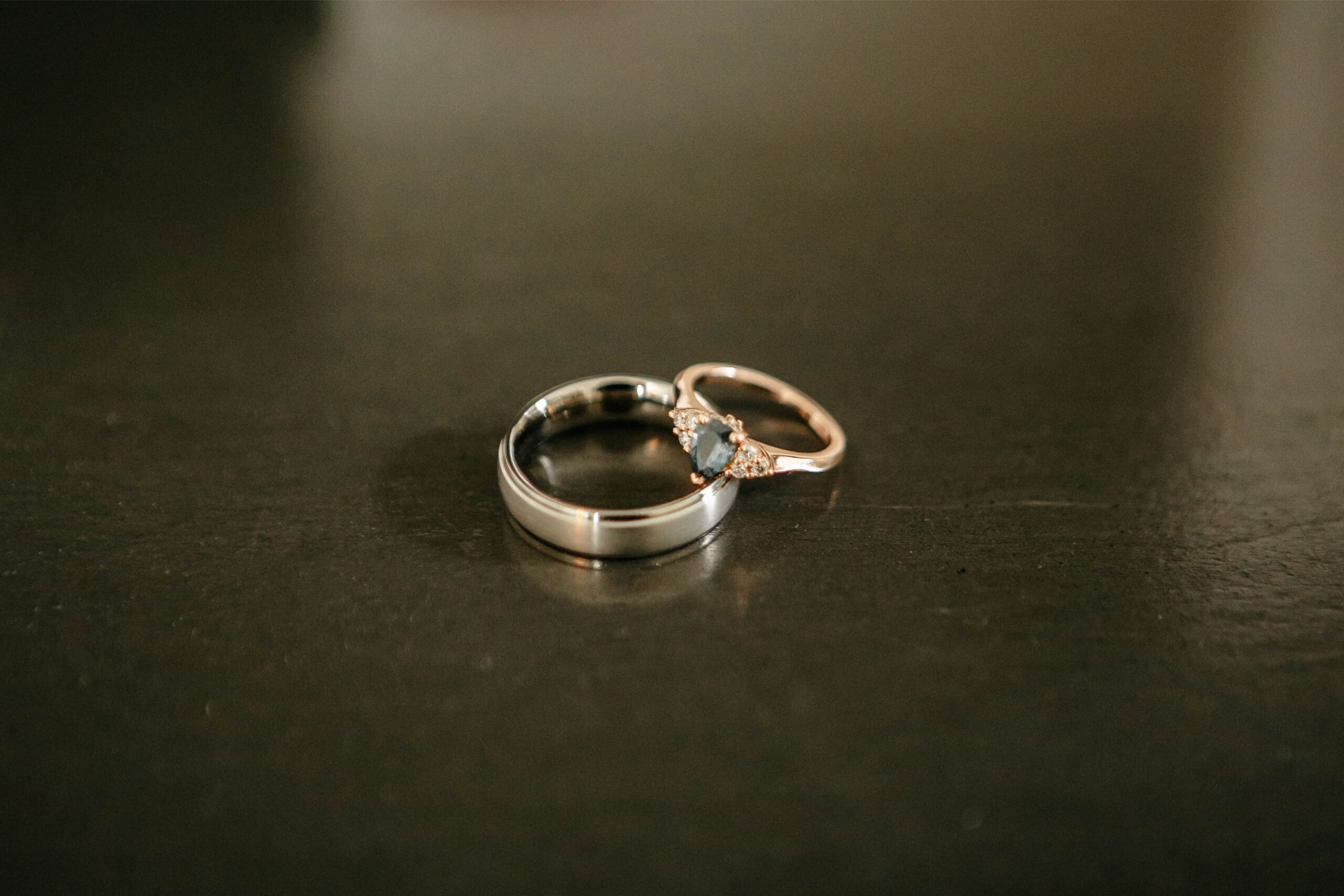 A gold wedding band with a green stone surrounded by diamonds rests on a silver wedding band at a wedding venue in Central Florida