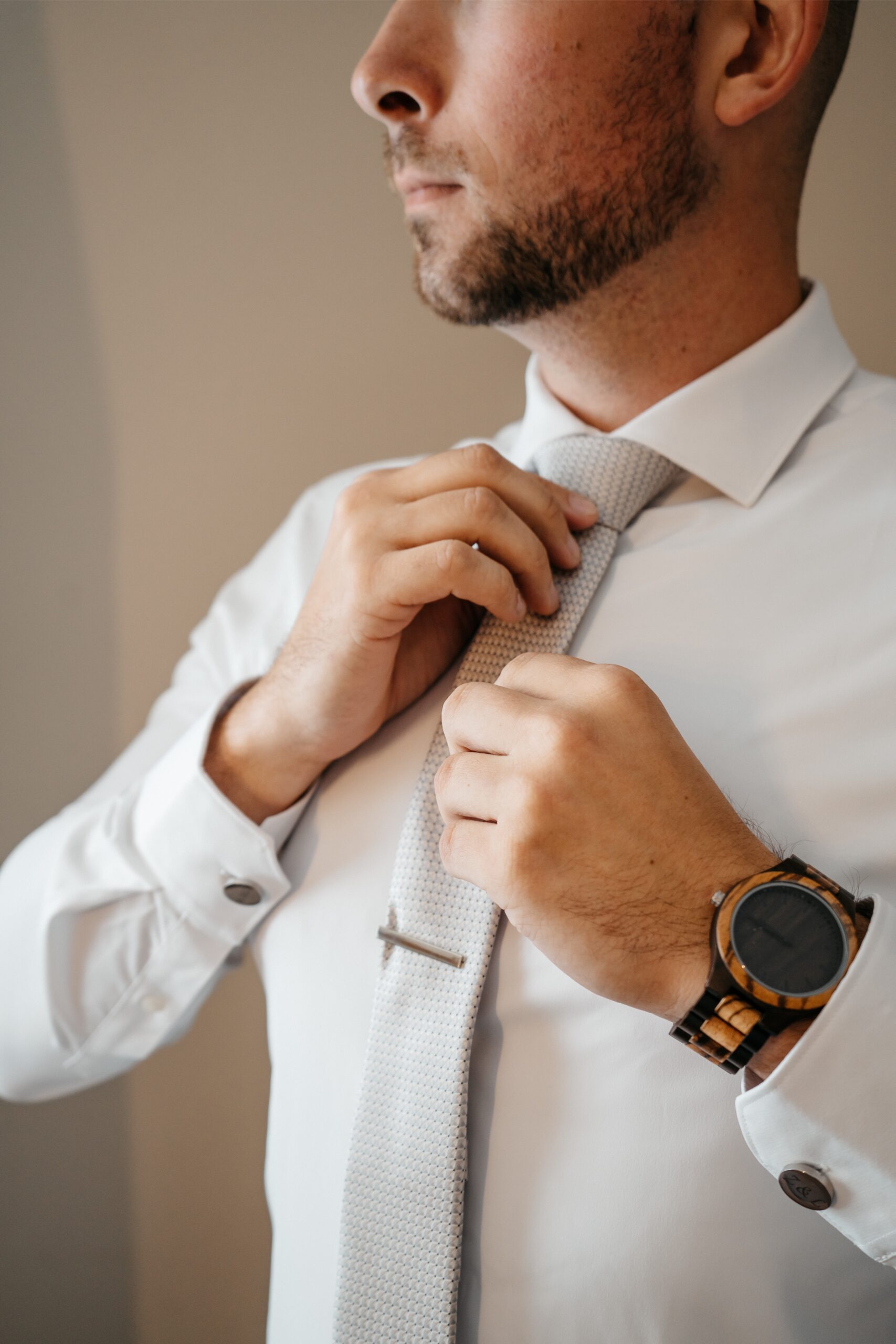 Central Florida wedding videographer captures a groom preparing for his wedding by adjusting his tie