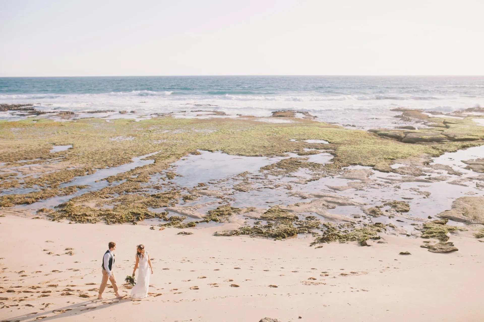 Aerial view of newlyweds walking a white-sand Gulf beach