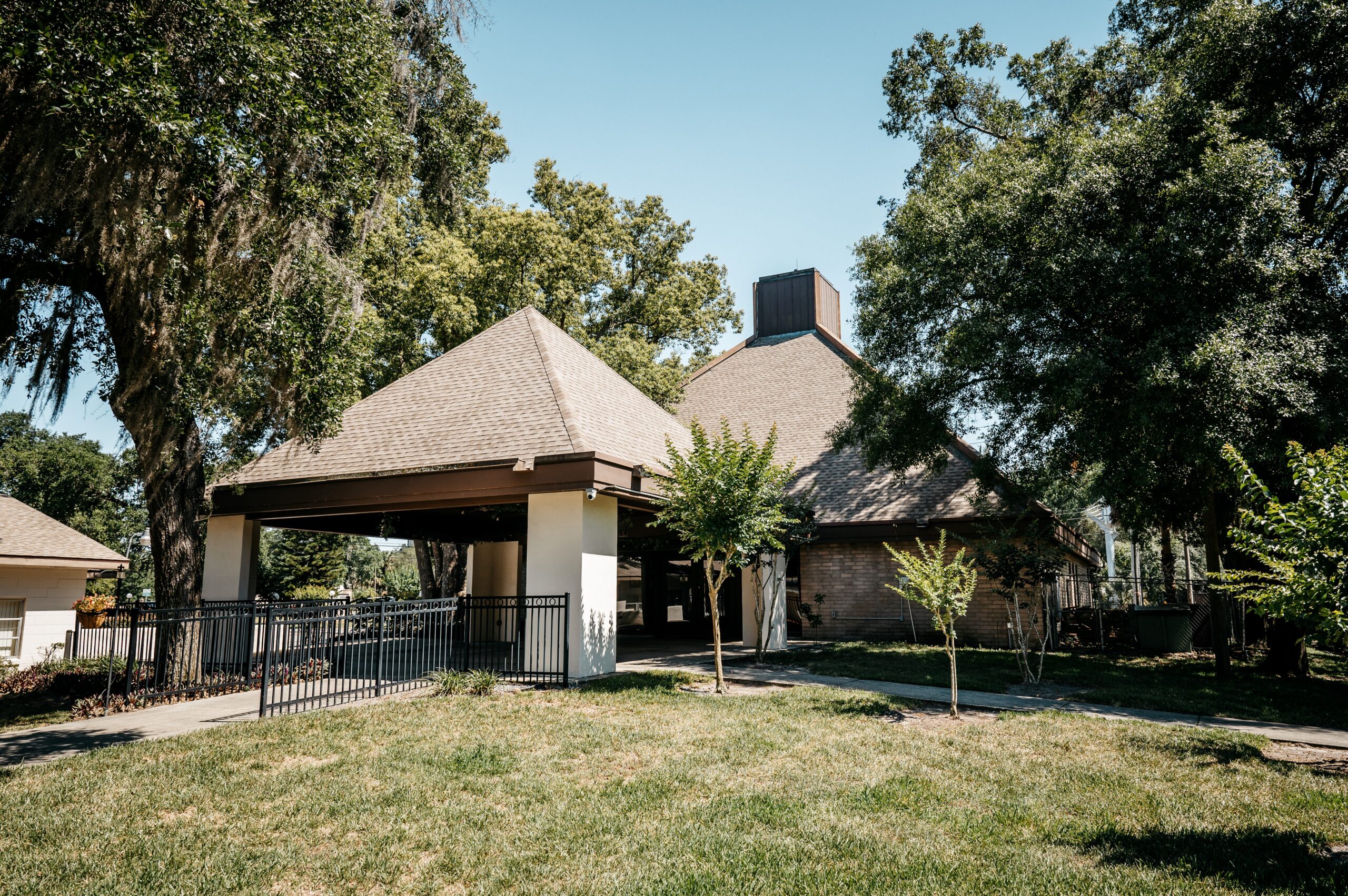 A brick building with a brown triangular roof surrounded by trees at altamonte chapel wedding