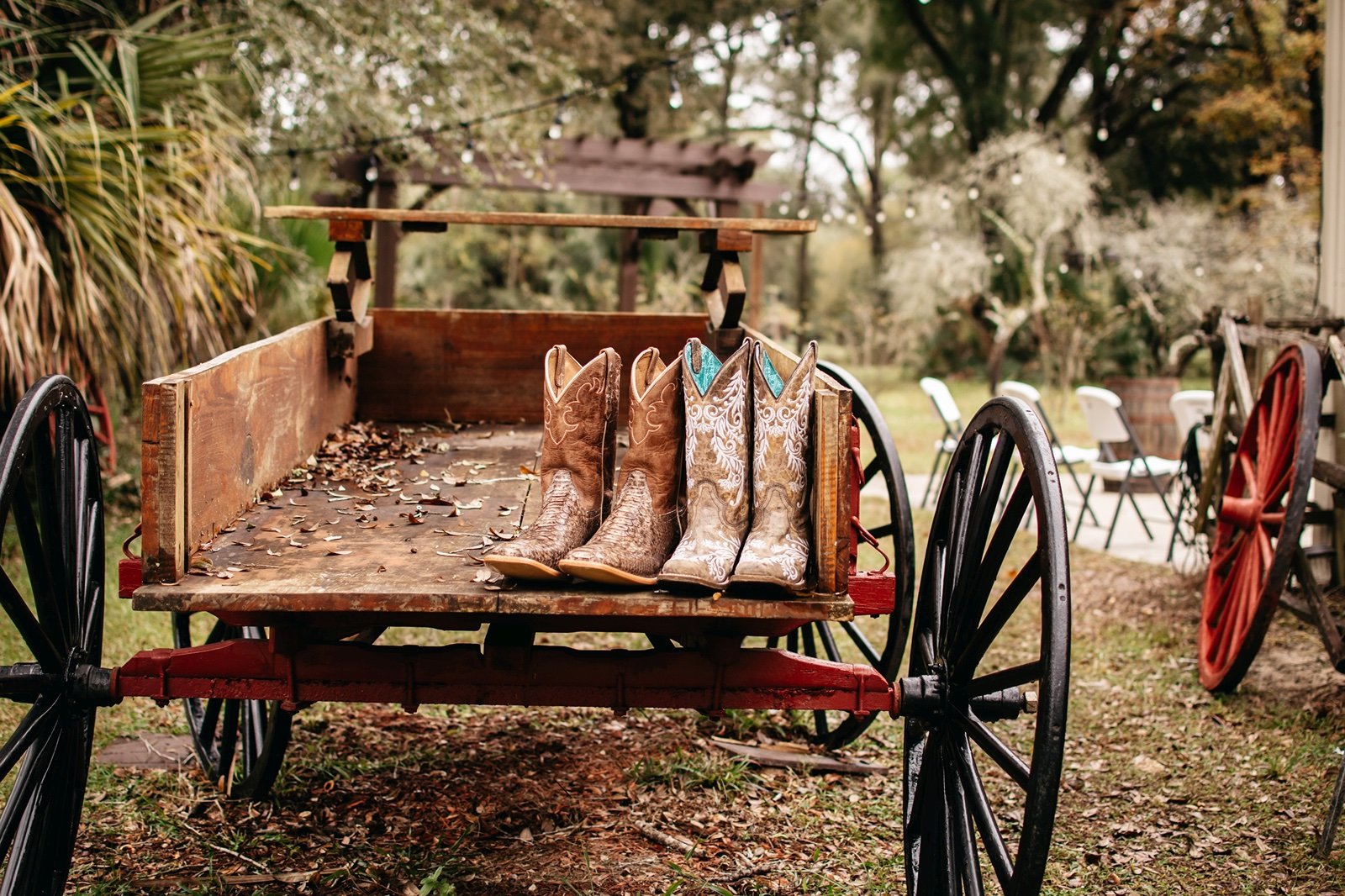 Two pairs of cowboy boots rest on a rustic wagon in a bushnell wedding venue
​