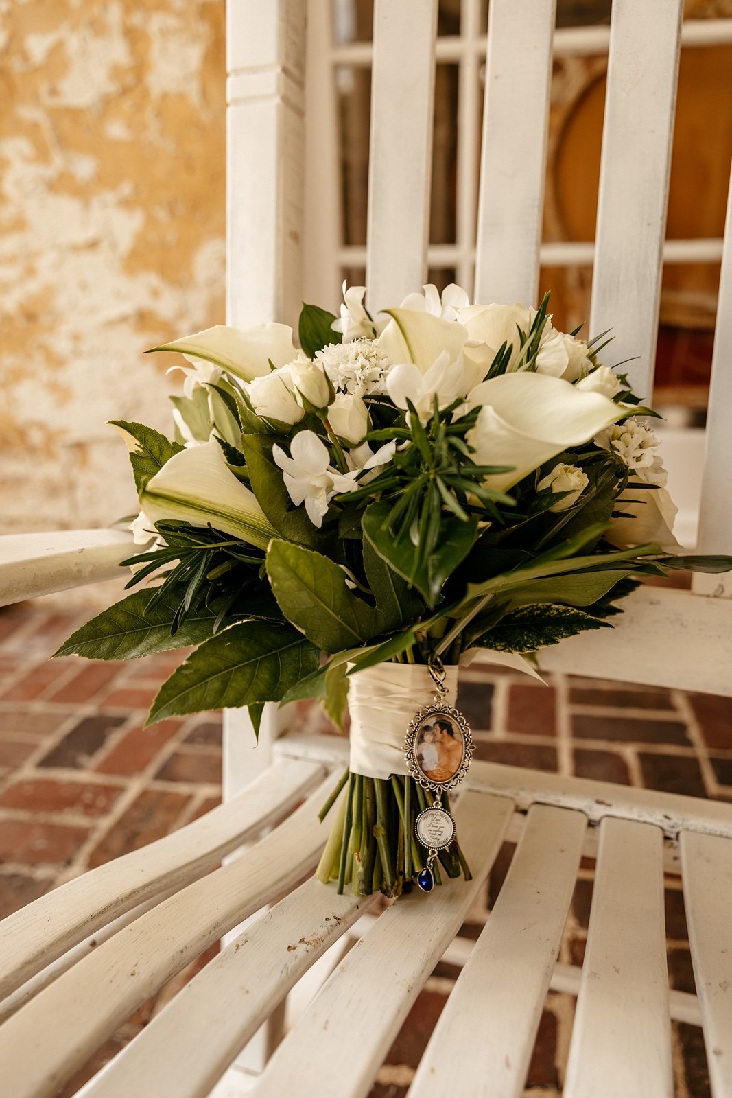 A white wedding bouquet wrapped in white ribbon holds a picture of a father and daughter to be used for a ​bella cosa wedding