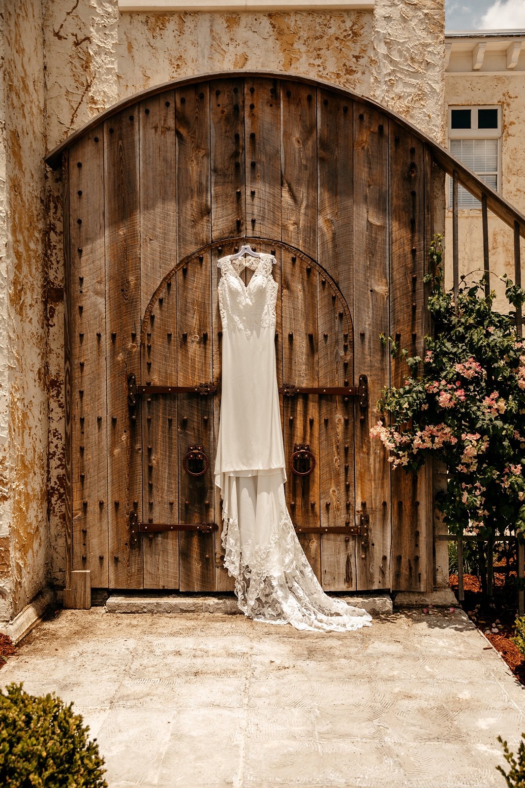 A lace wedding dress is hung on old-fashioned wooden doors to be displayed at the bella cosa lakeside wedding venue
