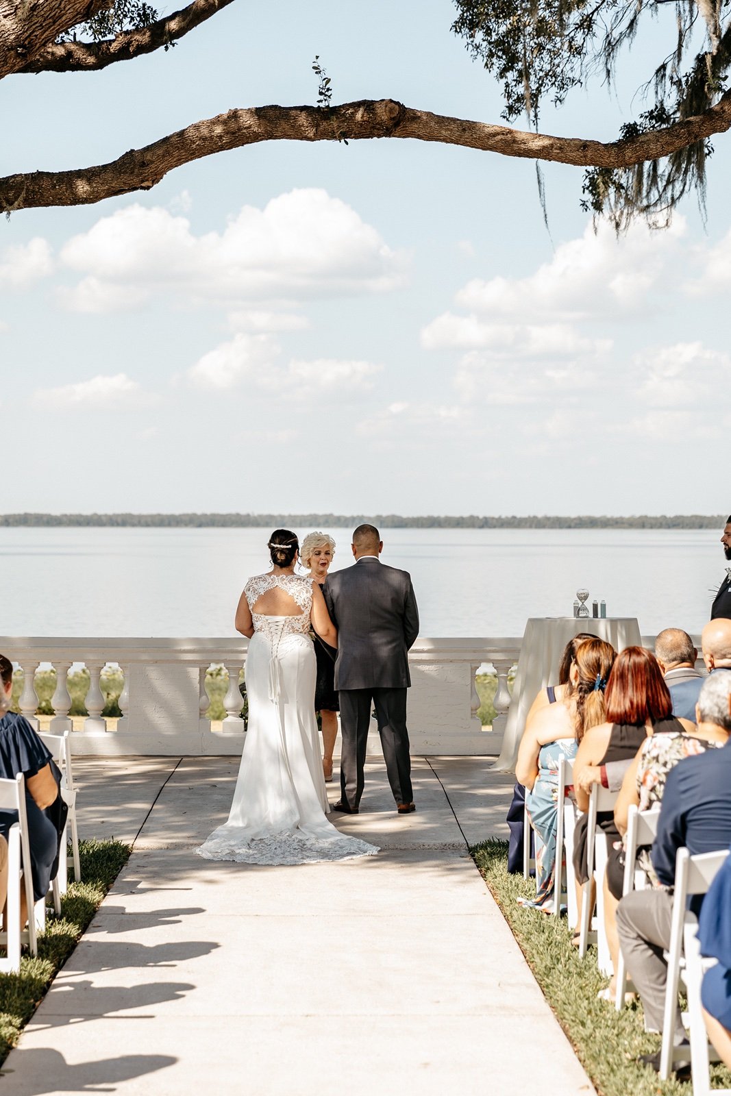 A bride and groom stand in front a waterfront view for their bella cosa lakeside wedding venue photos
