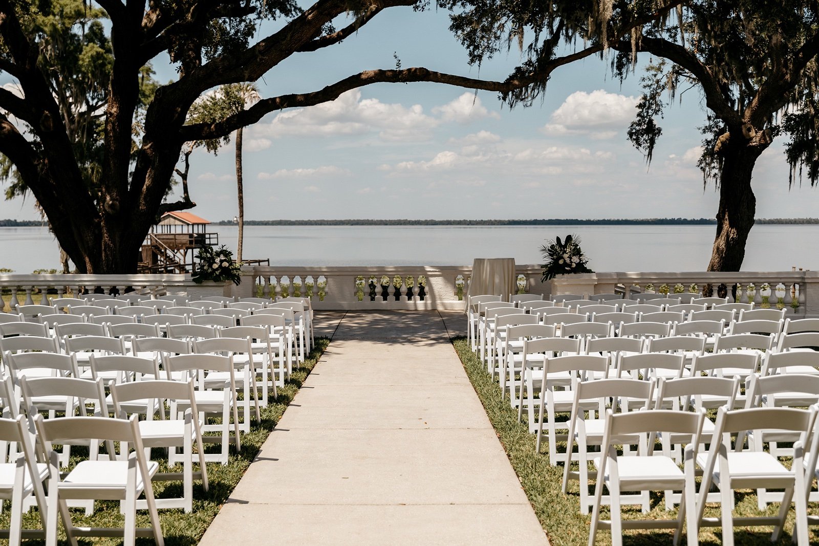 White chairs are placed in rows at the ​bella cosa lakeside wedding venue
