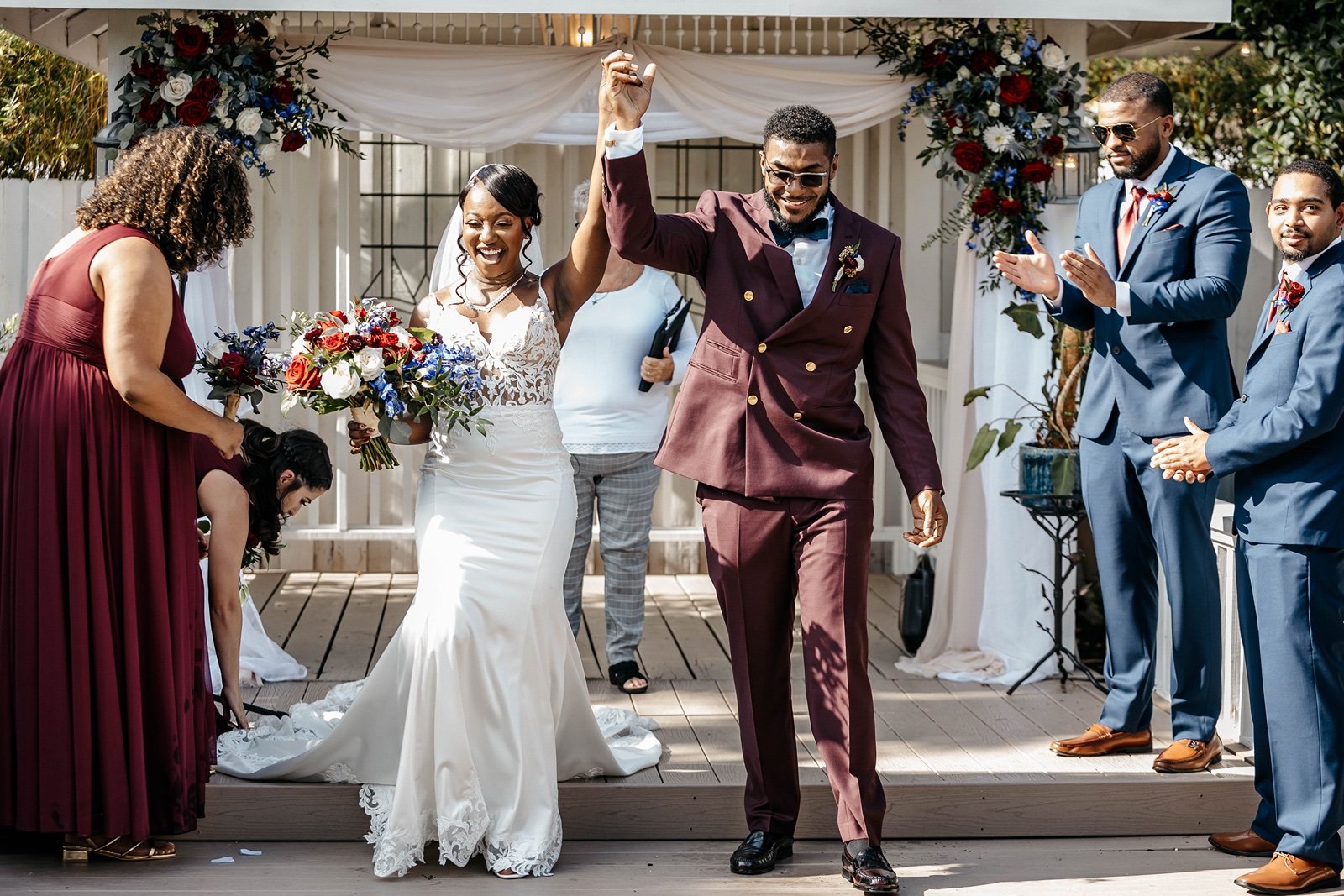 A bride and groom in a burgundy suit walk out celebrating at ​woodsy outdoor wedding venues in central florida