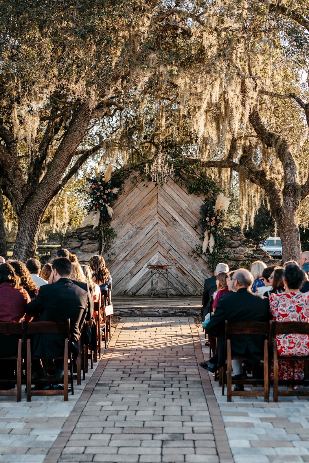 Large green trees with spanish moss stand before guests at outdoor wedding venues in central florida
