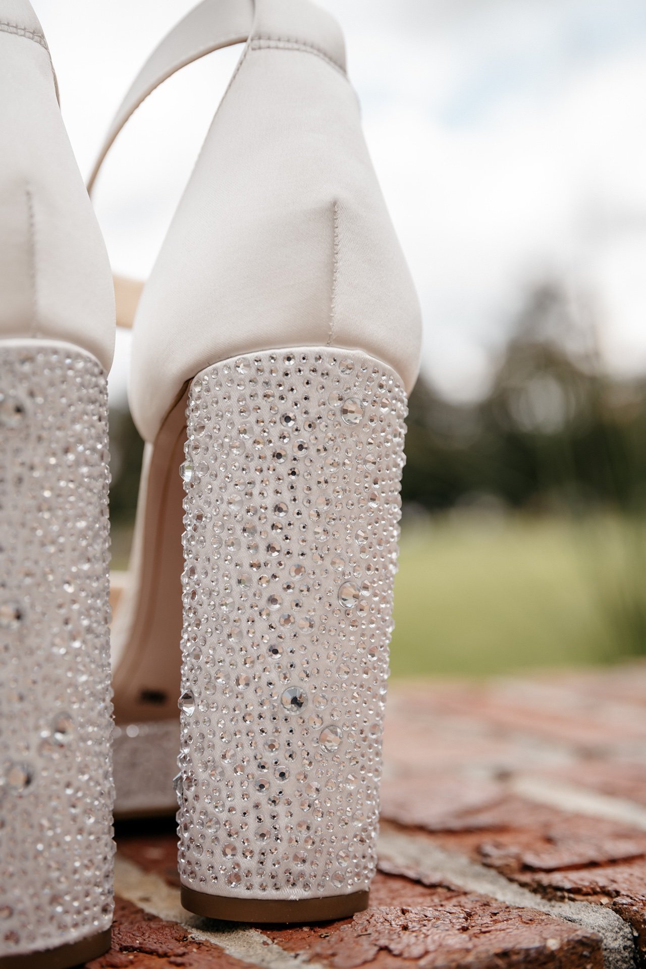 A pair of white high heels with gems are displayed for photos at a wedding in Florida