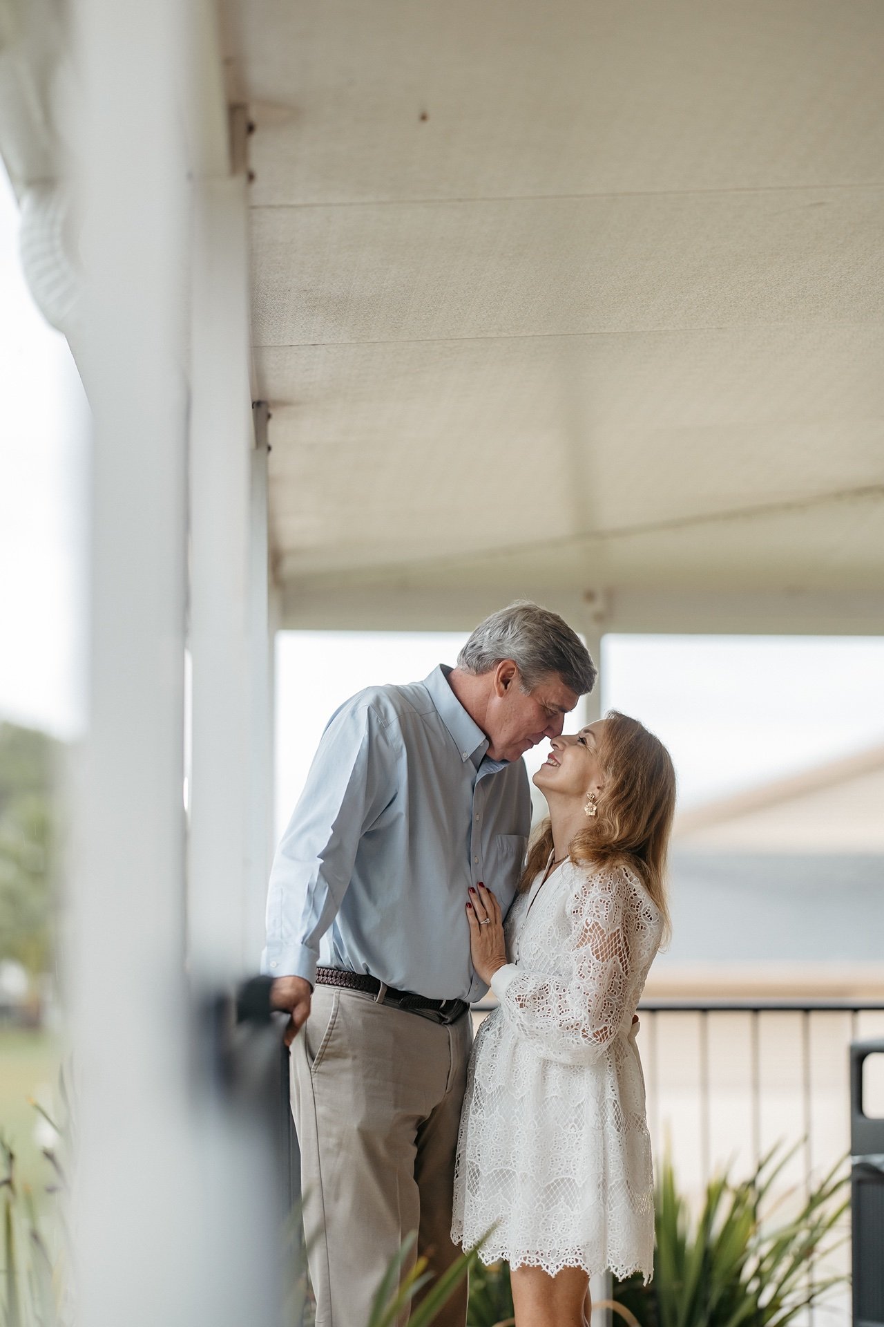 Bride and groom kiss on a porch