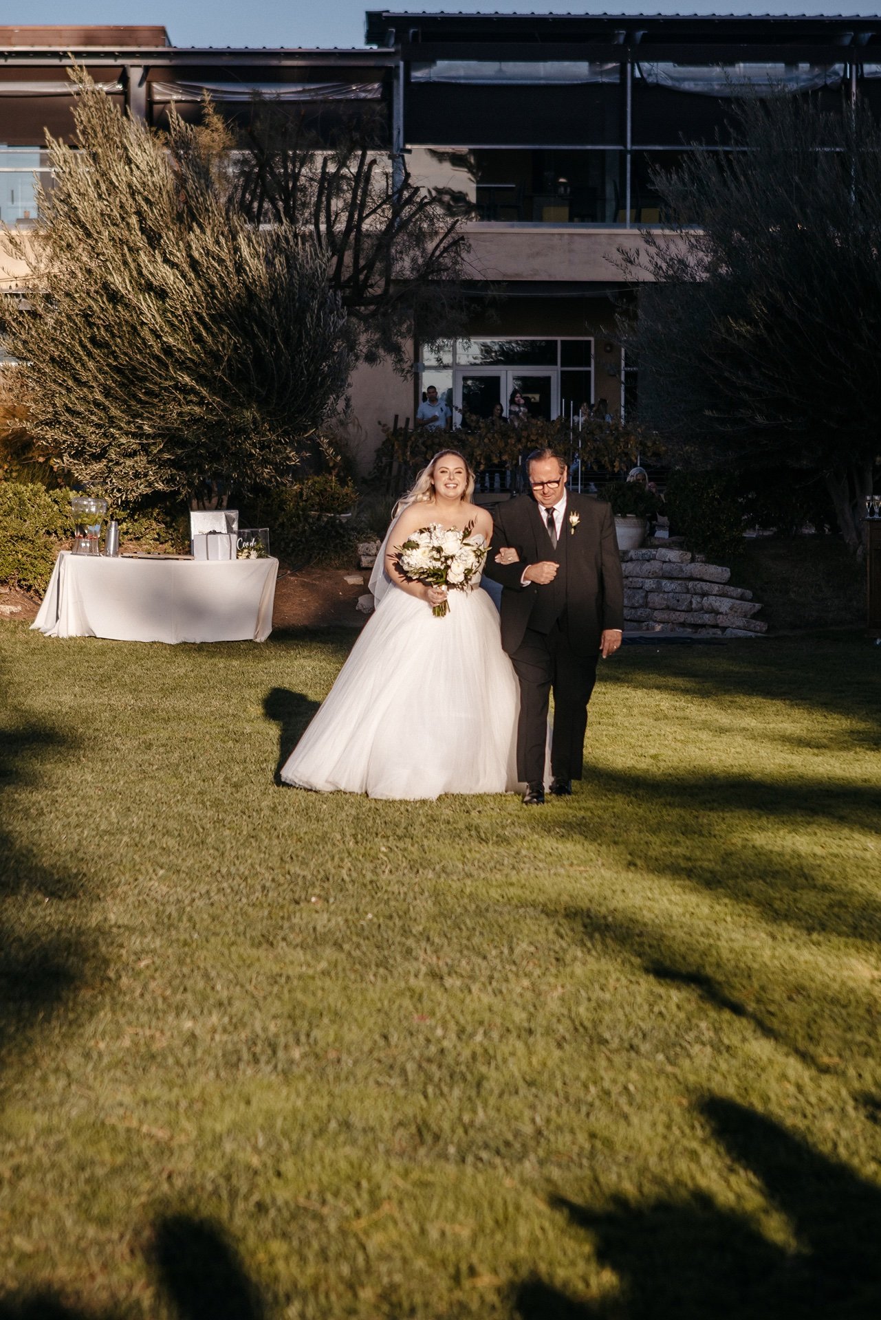 A bride is escorted down the aisle by her father at an outdoor wedding venue in Florida