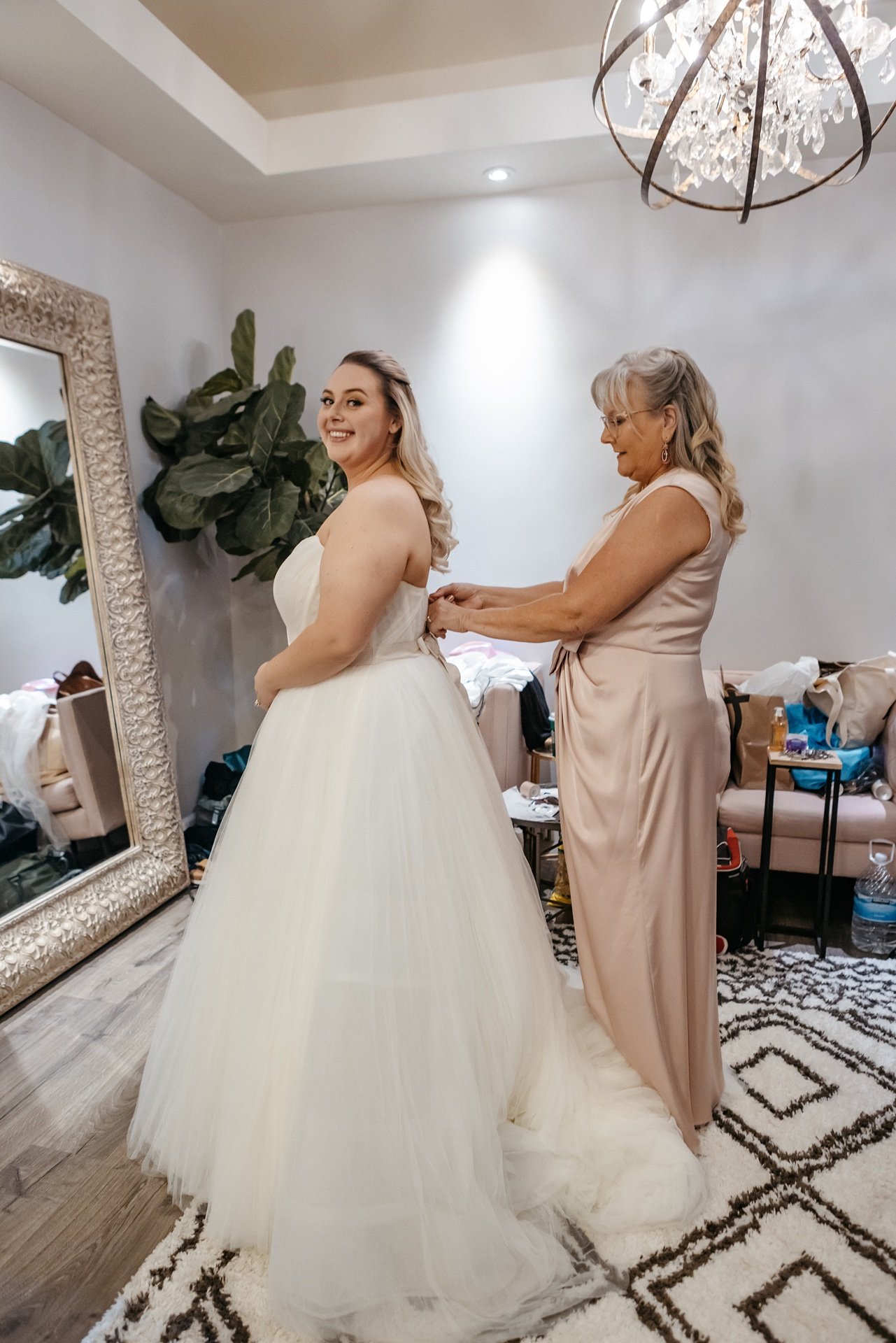 A bride smiles as her mother helps button her dress up before her wedding ceremony in Central Florida