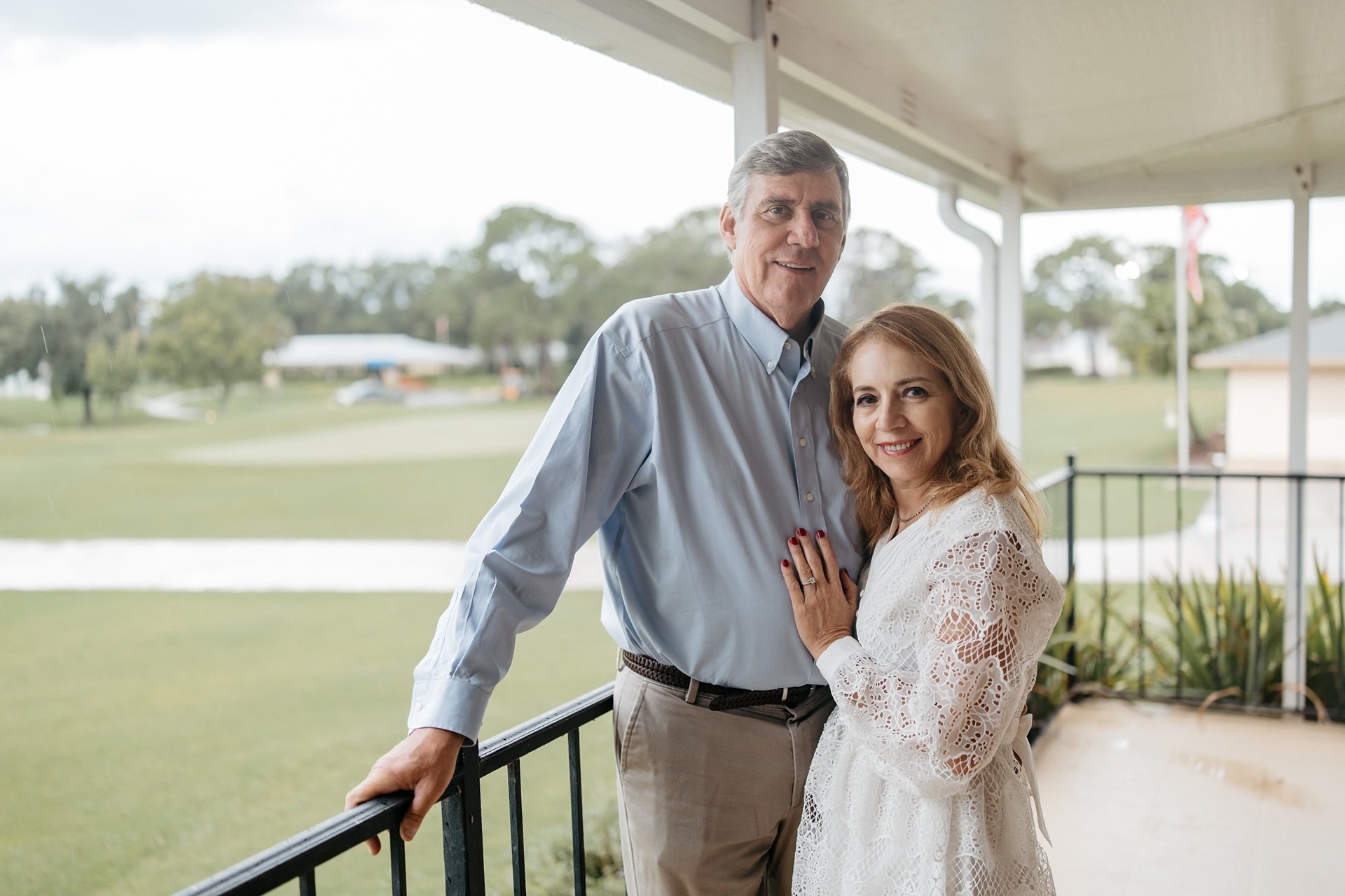 Bride and groom pose for a photo on a porch at their wedding
