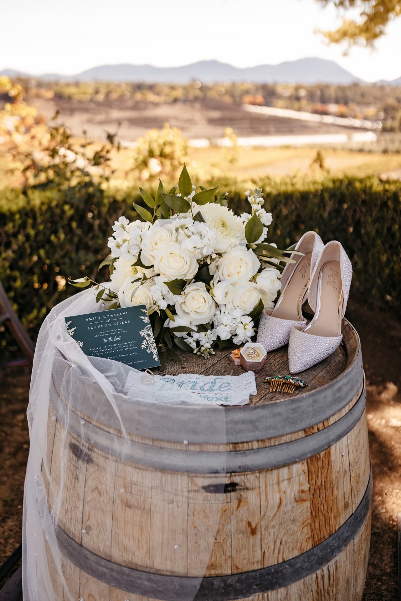 A white bouquet, sparkly heels, and other trinkets sit on top of a barrel at a wedding in Central Florida